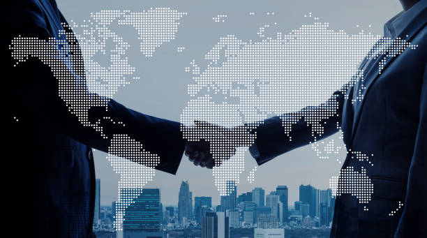 Business handshake beneath a dotted world map over a city skyline