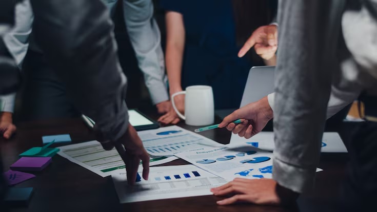 Team reviewing printed business charts and reports at a strategy table